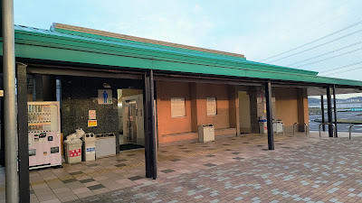 トイレ棟の外観。建物前にもゴミ箱と自販機が設置されています。