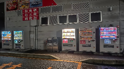 建物外の自動販売機コーナー（夜間）。自販機横にもゴミ箱が設置されています。