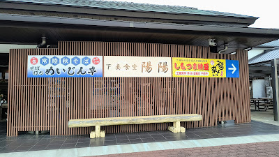 施設の看板。物産館の横にそば打ちめいじん亭・下妻食堂 陽陽・しもつま納豆「福よ来い」が並んでいます。