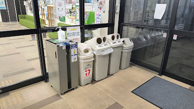 情報コーナー・トイレ入口付近のゴミ箱。缶・ビン・ペットボトルは24h利用可。「燃えるゴミは物産館側入口へ」の案内あり。