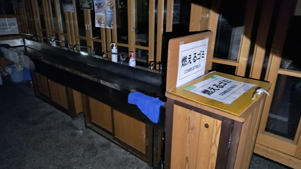 イートインコーナーの洗い場と燃えるゴミ用のゴミ箱。真っ暗だったのでライトで照らして撮影しました。