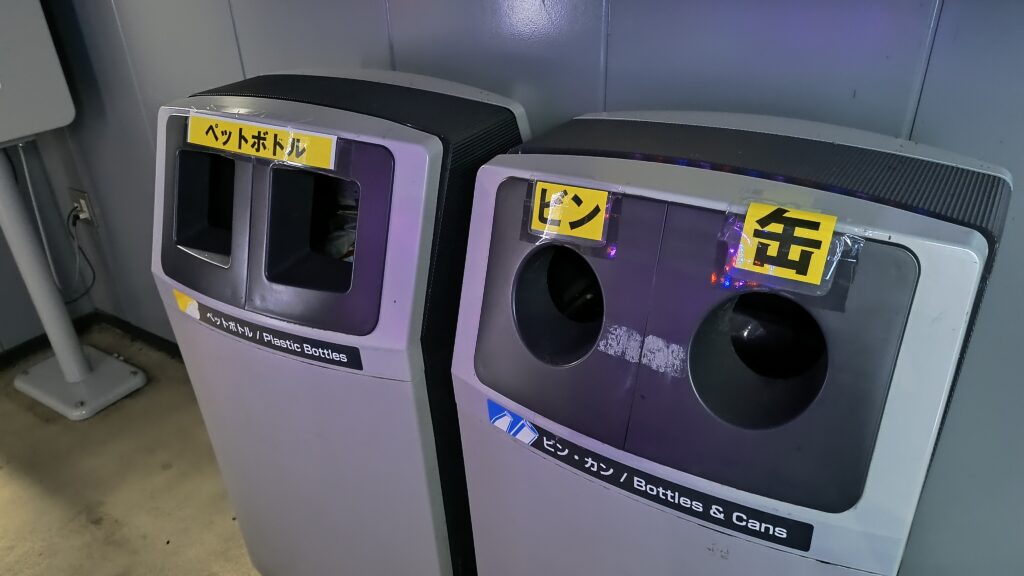 建物向かって右手側（屋外）にある自動販売機コーナーに24時間利用可能な缶・ビン、ペットボトル用のゴミ箱が設置。